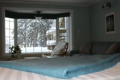 a bedroom with a bed and a couch and a window at Great Slave Lakeside Bed & Breakfast in Yellowknife