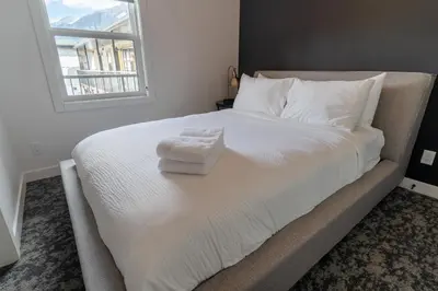 a white bed with a pile of towels on it at Basecamp Suites Canmore in Canmore