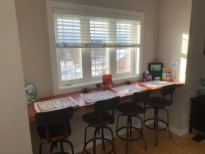 a kitchen with a bar with stools and a window at Dragonfly Inn Loft Suite in Sherwood Park