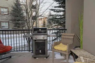 a patio with a grill and a table and chairs at Rustic Modern 2 Bed 2 Bath with Lakeview Pool and Hot Tub in Invermere