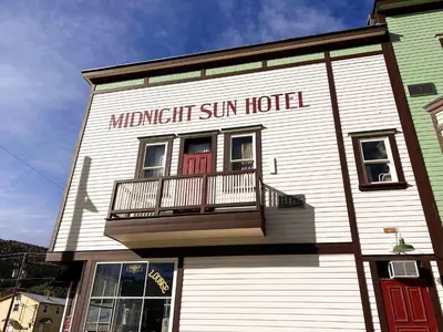 a white building with a sign that reads midnight sun hotel at Midnight Sun, a Coast Hotel in Dawson City