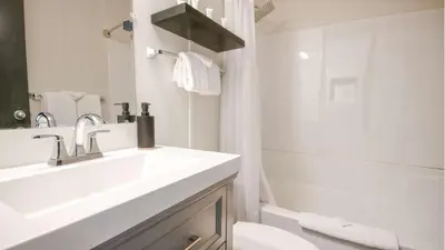 a white bathroom with a sink and a toilet at Midnight Sun, a Coast Hotel in Dawson City