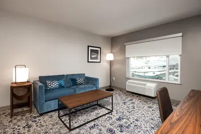 a living room with a blue couch and a window at Four Points by Sheraton Kelowna Airport in Kelowna