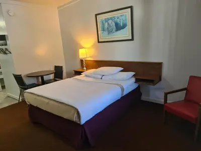 a hotel room with a bed and a red chair at Sundowner Motel in Cache Creek