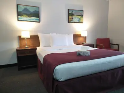 a hotel room with a large bed and a chair at Sundowner Motel in Cache Creek