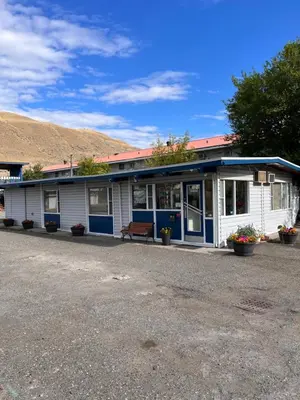 a white and blue building with a bench in front at Sundowner Motel in Cache Creek