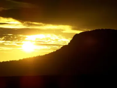 a sunset over a mountain with the sun in the sky at Eaglenest Manor Cowichan in Duncan