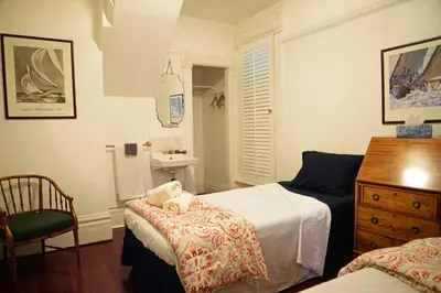 a bedroom with two beds and a chair and a sink at Vancouver Hideaway Guesthouse in Vancouver