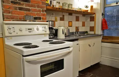 a kitchen with a white stove and a brick wall at Vancouver Hideaway Guesthouse in Vancouver