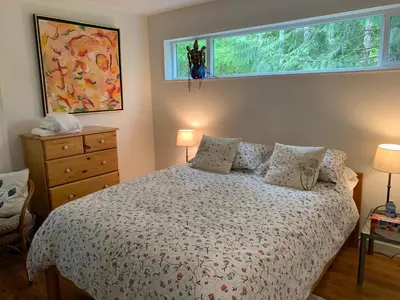 a bedroom with a bed with a window above it at Forest by the Sea Rentals in Merville