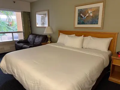 a bedroom with a large white bed and a chair at Westlock Inn & Conference Centre in Westlock