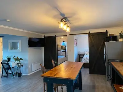 a living room with a table and a room with a bedroom at Sunrise Cabin secluded beach front accommodation in Sandspit