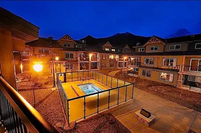 a large apartment building with a swimming pool at night at Mountain View Escape - Copperstone 2BR & Hot Tub in Canmore