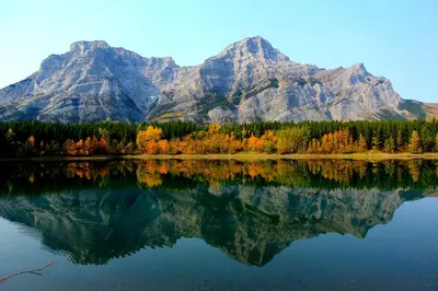 a mountain reflection in a lake with trees and mountains at Mountain View Escape - Copperstone 2BR & Hot Tub in Canmore