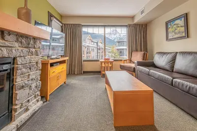 a living room with a couch and a fireplace at Mountain View Escape - Copperstone 2BR & Hot Tub in Canmore