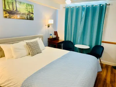 a bedroom with a bed with two chairs and a blue curtain at WindTower Resort - 1 Bed Hotel Room 166 in Canmore