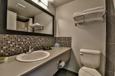 a bathroom with a sink and a toilet and a mirror at The View Hotel in Fort Saint James