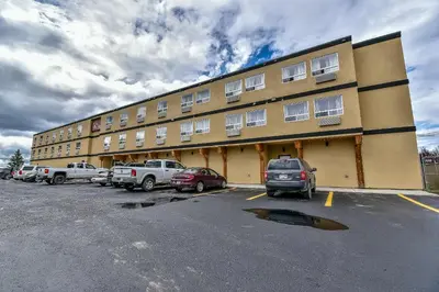 a large building with cars parked in a parking lot at The View Hotel in Fort Saint James