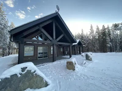 a log cabin in the snow with trees in the background at Timber Lodge in Valemount