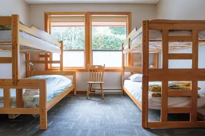 a bedroom with four bunk beds and a window at Whalers Guesthouse in Tofino