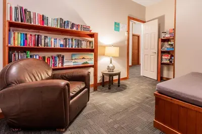 a bedroom with a couch and a book shelf with books at Whalers Guesthouse in Tofino