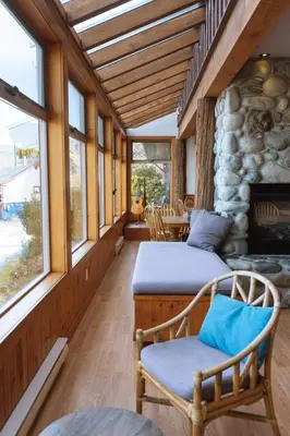 a porch with two beds and a table and windows at Whalers Guesthouse in Tofino