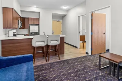 a room with a kitchen with a counter and chairs at Park Inn by Radisson, Kelowna in Kelowna
