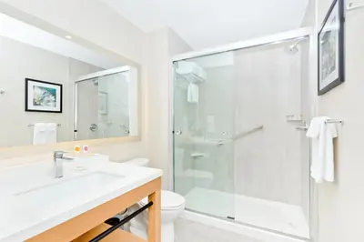 a white bathroom with a shower and a sink at Hyatt Place Kelowna in Kelowna