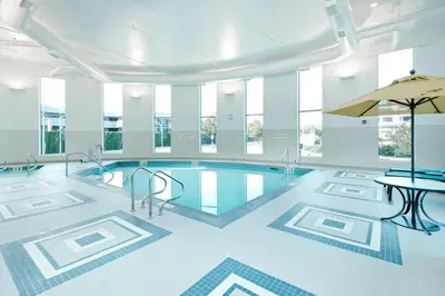 a pool in a building with a table and chairs at Hyatt Place Kelowna in Kelowna