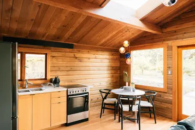 a kitchen with wooden walls and a table and a stove at Bodega Ridge & Cove Cabins in Fernwood
