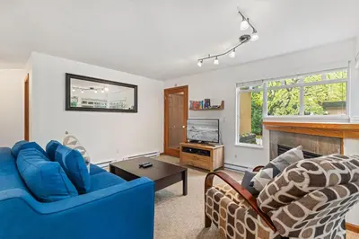 a living room with two blue chairs and a fireplace at Stoney Creek Sunpath by Whistler Premier in Whistler