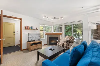 a living room with a blue couch and a tv at Stoney Creek Sunpath by Whistler Premier in Whistler