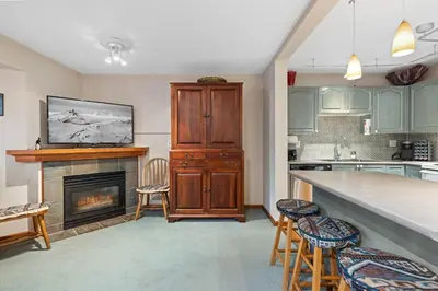 a kitchen with a fireplace and a counter with chairs at Stoney Creek Sunpath by Whistler Premier in Whistler