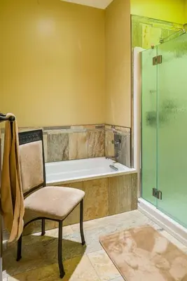 a bathroom with a tub and a chair and a shower at Kootenay Wild Guest Suites in Nelson