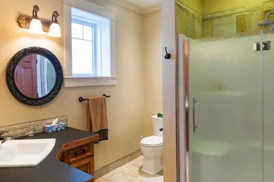 a bathroom with a shower and a sink and a toilet at Kootenay Wild Guest Suites in Nelson