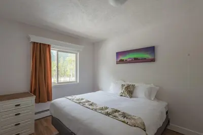 a white bedroom with a bed and a window at David Thompson Resort in Cline River