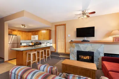 a kitchen and a living room with a fireplace at Symphony by Whistler Premier in Whistler