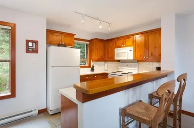a kitchen with a white refrigerator and wooden cabinets at Treeline Townhome by Whistler Premier in Whistler