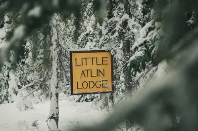 a sign that reads little atkin lodge in the snow at Little Atlin Lodge in Tagish