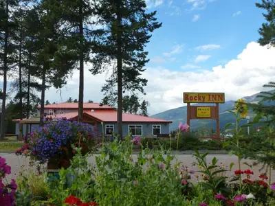 a sign for a lucky inn with flowers in the foreground at Rocky Inn in Valemount