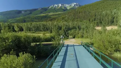 a bridge over a river with a mountain in the background at Summit River Lodge & Campsites in Valemount