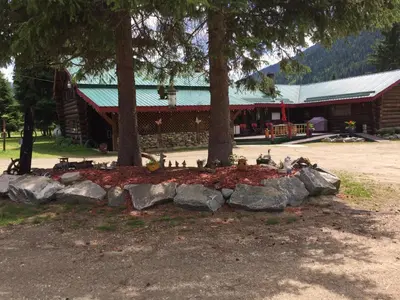 a log cabin with trees and rocks in front of it at Summit River Lodge & Campsites in Valemount