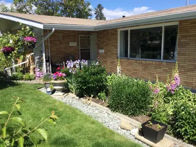 a garden in front of a house with flowers at Your home away from home in Kelowna