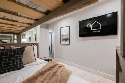 a bedroom with a bed and a tv on a wall at The Woods by Outpost Whistler in Whistler