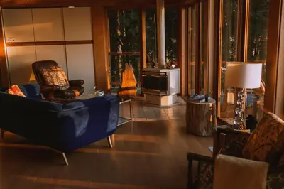 a living room with a blue chair and a fireplace at The Sanctuary Retreat Salt Spring Island in Salt Spring Island