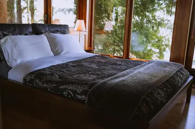a bed in a room with a large window at The Sanctuary Retreat Salt Spring Island in Salt Spring Island