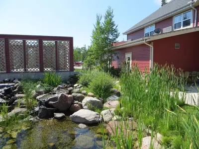 a garden with a stream in front of a house at Village Creek Country Inn in Westerose