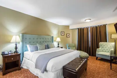 a large bedroom with a large bed and two chairs at Quality Hotel in Drumheller