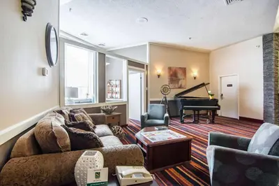 a living room with a couch and a piano at Quality Hotel in Drumheller