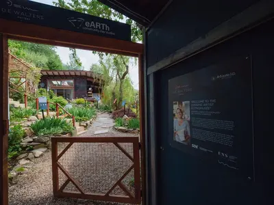 a sign on a building with a garden in the background at eARTh studios GallerySuite in Nelson